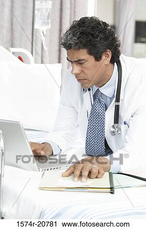 Side profile of a male doctor using a laptop View Large Photo Image Stock Image - Side profile of a male doctor using a laptop. Fotosearch