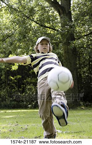 Boy playing with a soccer ball in a field View Large Photo Image Stock Photo - Boy playing with a soccer ball in a field. Fotosearch