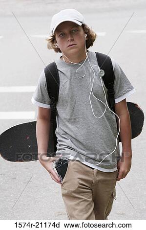 Stock Image - Close-up of a boy carrying a skateboard and a backpack. Fotosearch