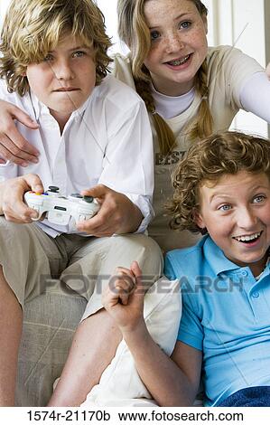 Stock Image - Close-up of a boy playing a video game with his friends. Fotosearch
