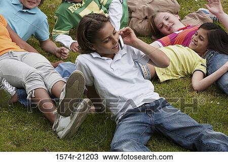 High angle view of a boy using a mobile phone with his friends lying beside him View Large Photo Image Stock Image - High angle view of a boy using a mobile phone with his friends lying beside him. Fotosearch