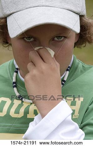 Stock Image - Portrait of a boy blowing his nose. Fotosearch