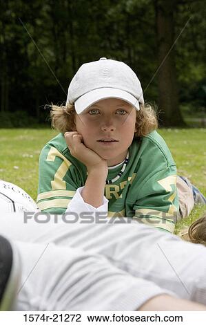 Portrait of a boy lying on grass with his hand on his chin View Large Photo Image Stock Image - Portrait of a boy lying on grass with his hand on his chin. Fotosearch
