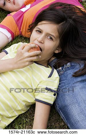 Portrait of a girl eating an apple with her head resting on another girl View Large Photo Image Stock Image - Portrait of a girl eating an apple with her head resting on another girl. Fotosearch