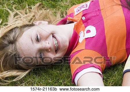 Portrait of a girl lying on the grass and smiling View Large Photo Image Stock Image - Portrait of a girl lying on the grass and smiling. Fotosearch