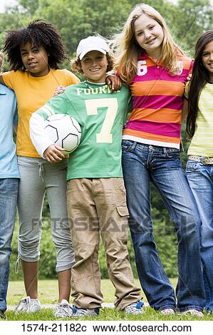 Stock Image - Portrait of three girls and a boy standing side by side and smiling. Fotosearch