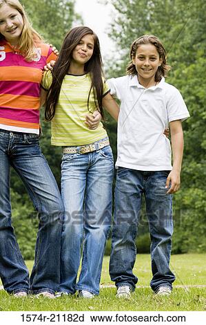 Portrait of two girls and a boy standing in a park with their arms around each other View Large Photo Image Stock Image - Portrait of two girls and a boy standing in a park with their arms around each other. Fotosearch
