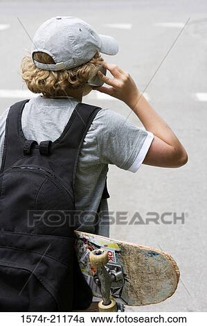Rear view of a boy using a mobile phone View Large Photo Image Stock Image - Rear view of a boy using a mobile phone. Fotosearch