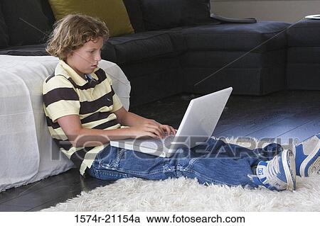 Side profile of a boy sitting on the floor using a laptop View Large Photo Image Stock Image - Side profile of a boy sitting on the floor using a laptop. Fotosearch