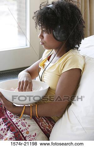 Side profile of a girl listening to music and holding a bowl View Large Photo Image Stock Photo - Side profile of a girl listening to music and holding a bowl. Fotosearch