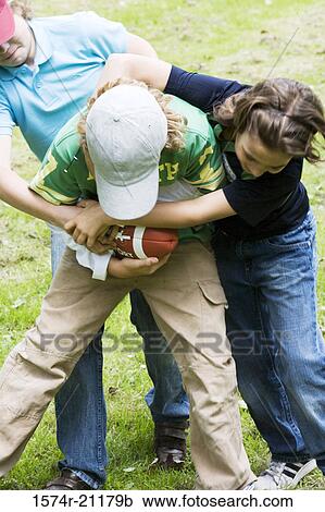 Stock Image - Three children playing with a football. Fotosearch