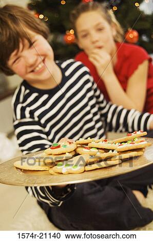 Close-up of a brother holding Christmas cookies on a plate with his sister in the background View Large Photo Image Stock Image - Close-up of a brother holding Christmas cookies on a plate with his sister in the background. Fotosearch