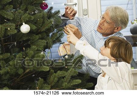 Stock Photograph - Close-up of a grandfather and his grandson looking at Christmas tree. Fotosearch