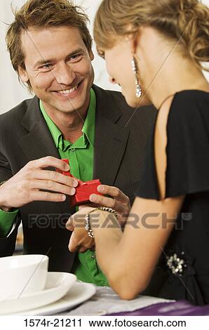 Close-up of a mid adult man giving a Christmas present to a young woman View Large Photo Image Stock Image - Close-up of a mid adult man giving a Christmas present to a young woman. Fotosearch