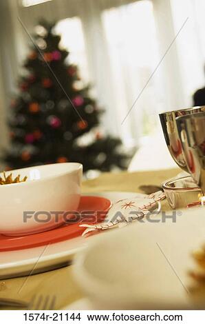 Close-up of bowls and plates on a table with a Christmas tree in the background View Large Photo Image Picture - Close-up of bowls and plates on a table with a Christmas tree in the background. Fotosearch