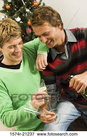 Stock Photo - High angle view of two mid adult men holding champagne flutes and smiling. Fotosearch