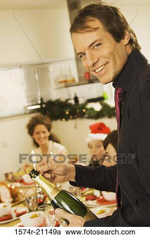 Portrait of a mid adult man holding a champagne bottle at a dining table View Large Photo Image Stock Image - Portrait of a mid adult man holding a champagne bottle at a dining table. Fotosearch