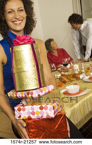 Portrait of a mid adult woman holding a stack of Christmas presents and smiling View Large Photo Image Stock Photo - Portrait of a mid adult woman holding a stack of Christmas presents and smiling. Fotosearch