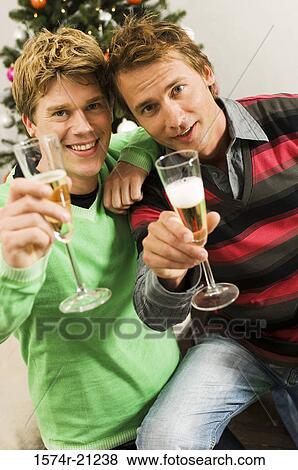 Stock Photo - Portrait of two mid adult men holding champagne flutes and smiling. Fotosearch