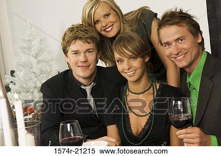 Stock Photography - Portrait of two young women with two mid adult men smiling at a Christmas party. Fotosearch