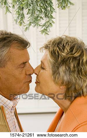 Stock Image - Side profile of a senior couple kissing each other. Fotosearch