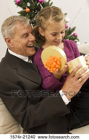 Side profile of a senior man with his granddaughter opening a Christmas present View Large Photo Image Stock Image - Side profile of a senior man with his granddaughter opening a Christmas present. Fotosearch