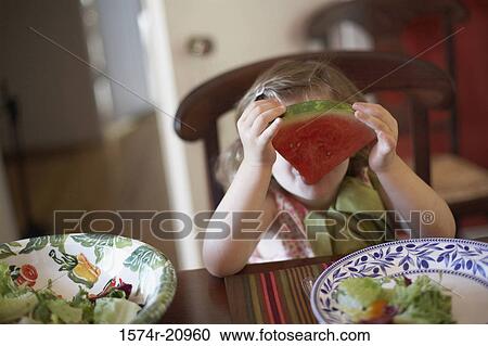 Close-up of a girl holding a slice of watermelon in front of her face View Large Photo Image Stock Image - Close-up of a girl holding a slice of watermelon in front of her face. Fotosearch