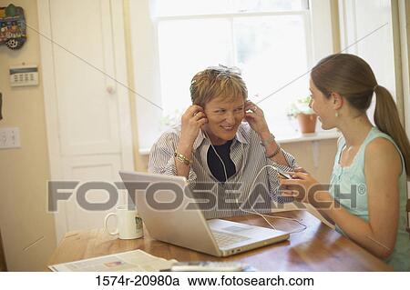Close-up of a mature woman wearing headphones with her granddaughter sitting beside her View Large Photo Image Stock Image - Close-up of a mature woman wearing headphones with her granddaughter sitting beside her. Fotosearch