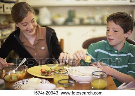 Stock Image - Close-up of a teenage girl having breakfast with her brother. Fotosearch