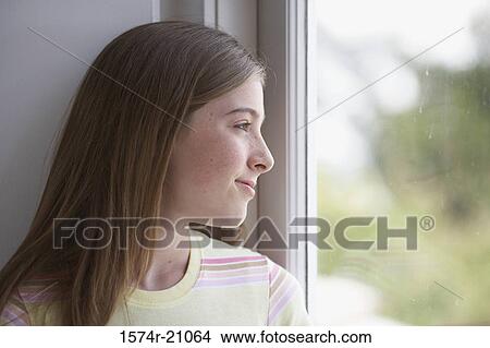 Close-up of a teenage girl looking through a window View Large Photo Image Picture - Close-up of a teenage girl looking through a window. Fotosearch
