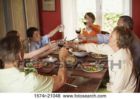 Family toasting with glasses at a dining table View Large Photo Image Stock Photo - Family toasting with glasses at a dining table. Fotosearch