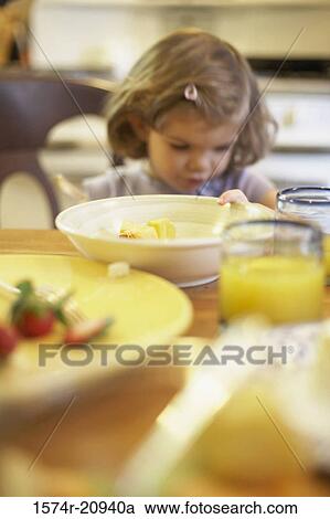 Stock Image - Girl sitting at a dining table. Fotosearch