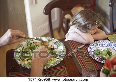 High angle view of a girl sitting at a dining table looking displeased View Large Photo Image Stock Photo - High angle view of a girl sitting at a dining table looking displeased. Fotosearch