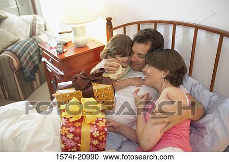High angle view of a mid adult couple smiling with their daughter in the bed View Large Photo Image Stock Image - High angle view of a mid adult couple smiling with their daughter in the bed. Fotosearch