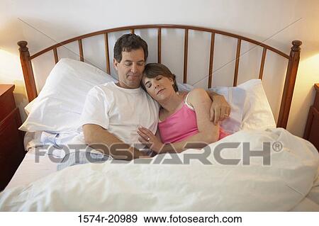 Stock Photo - High angle view of a mid adult couple sleeping in the bed. Fotosearch
