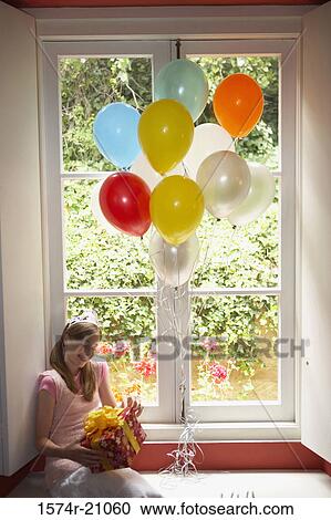 High angle view of a teenage girl sitting on a window ledge and holding her birthday present View Large Photo Image Stock Image - High angle view of a teenage girl sitting on a window ledge and holding her birthday present. Fotosearch