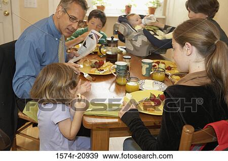 Stock Photo - Mid adult couple having breakfast with their two daughters and two sons. Fotosearch