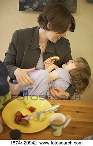 Stock Image - Mid adult woman playing with her daughter at a dining table. Fotosearch