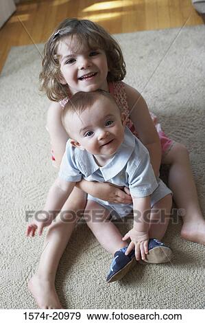Stock Photo - Portrait of a girl hugging her brother and smiling. Fotosearch