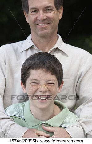 Stock Image - Portrait of a mid adult man smiling with his son. Fotosearch