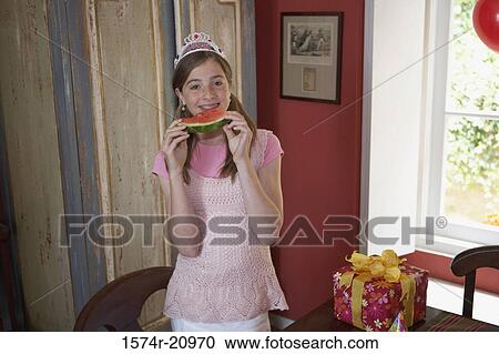 Stock Image - Portrait of a teenage girl eating a slice of watermelon. Fotosearch