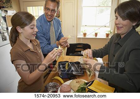 Stock Image - Side profile of a mid adult couple preparing breakfast with their daughter. Fotosearch