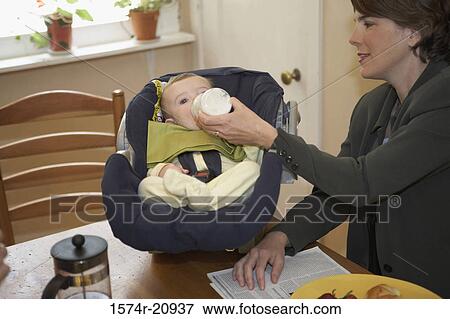 Side profile of a mid adult woman feeding milk to her son with a baby bottle View Large Photo Image Stock Photo - Side profile of a mid adult woman feeding milk to her son with a baby bottle. Fotosearch