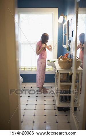 Side profile of a teenage girl combing her hair in the bathroom View Large Photo Image Stock Photograph - Side profile of a teenage girl combing her hair in the bathroom. Fotosearch