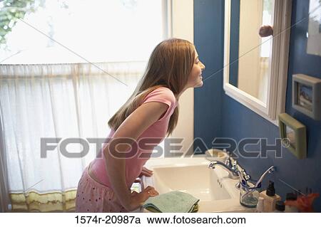 Side profile of a teenage girl looking at a mirror in the bathroom View Large Photo Image Stock Image - Side profile of a teenage girl looking at a mirror in the bathroom. Fotosearch