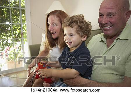Close-up of a boy sitting with his grandparents and playing a video game View Large Photo Image Stock Image - Close-up of a boy sitting with his grandparents and playing a video game. Fotosearch