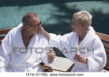 Stock Image - Close-up of a mature couple holding champagne flutes at poolside. Fotosearch