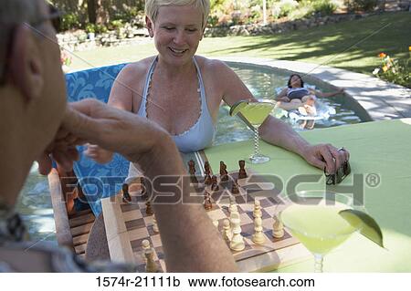 Close-up of a mature couple playing chess at poolside View Large Photo Image Stock Image - Close-up of a mature couple playing chess at poolside. Fotosearch