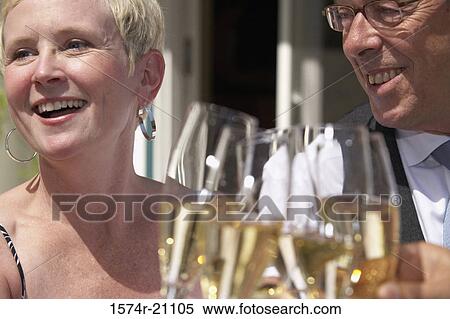 Stock Photography - Close-up of a mature couple smiling and toasting with champagne flutes. Fotosearch