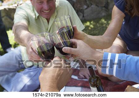 Stock Image - Close-up of a mature man and his friends toasting with wineglasses. Fotosearch